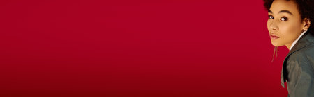 A young woman expresses deep emotions while looking contemplatively against a bold red background.の写真素材