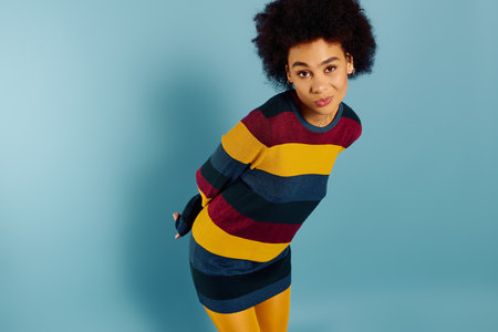 A young emotional woman expresses feelings while dressed in vibrant, striped clothing.