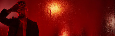 Stylish man in suit posing in red lights.