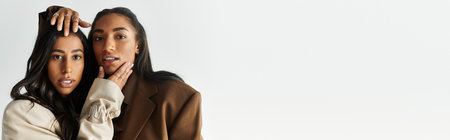 Two fashionable young women pose confidently in trendy attire, highlighting modern style.の写真素材