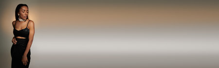 Appealing young woman with dark hair posing actively on gray lighted backdrop.の写真素材