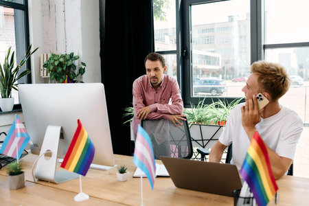 A couple collaborates in a vibrant office adorned with pride flags, celebrating creativity.の写真素材