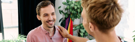 Two men share a warm smile, enjoying a playful interaction in a bright, plant filled space.の写真素材