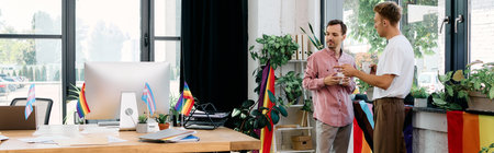 Two well dressed men share a heartfelt conversation in a colorful office setting.の写真素材