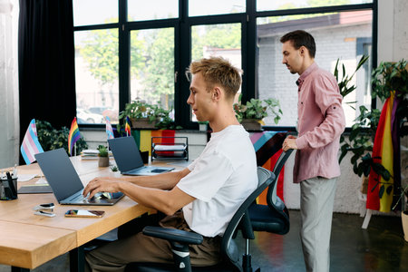 Two men collaborate in a bright workspace full of greenery and pride flags.の写真素材