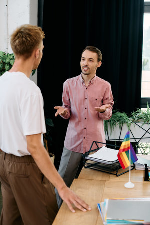 Two young men engage in a lively discussion, sharing smiles in a stylish office environment.の写真素材