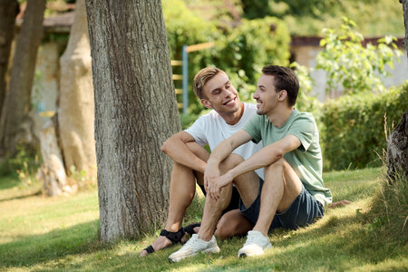 A loving couple relaxes together on the grass, sharing laughter and smiles under the sun.の写真素材