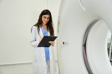 Professional doctor in a lab coat reviews patient diagnostics near advanced MRI equipment.の写真素材