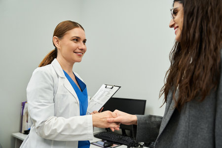 A gynecologist in a lab coat discusses health issues with a female patient in a clinic.の写真素材