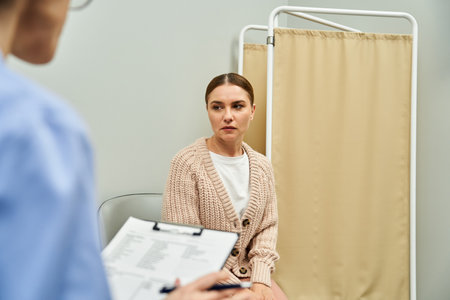 A gynecologist discusses health concerns with a patient in a professional clinic setting.の写真素材