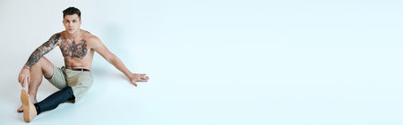 A tattooed young man showcases his prosthetic leg in a thoughtful pose, exuding confidence and artistry.の写真素材