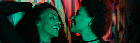 Two friends share laughter and joy in a colorful setting, embodying friendship and happiness.の写真素材