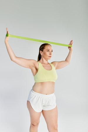 A determined woman exercises with a resistance band in a brightly lit studio, showcasing her...