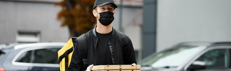 A delivery man in a mask is bringing meals into a busy office building during lunchtime hours.の写真素材