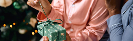 Two women joyfully exchange gifts amid festive decor and warmth.