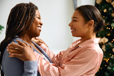 Warm smiles and joyful embraces showcase love between two women in festive attire.の写真素材
