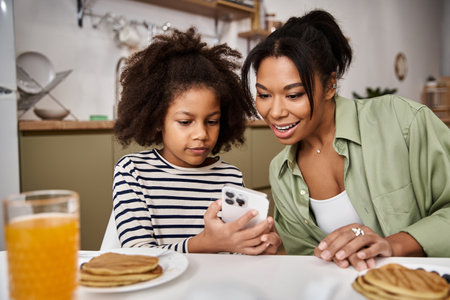 A loving mother shares a moment with her little daughter while enjoying breakfast together.の写真素材