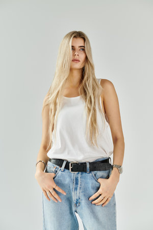 Bright studio features a beautiful young woman in a stylish tank top and jeans, exuding confidence.