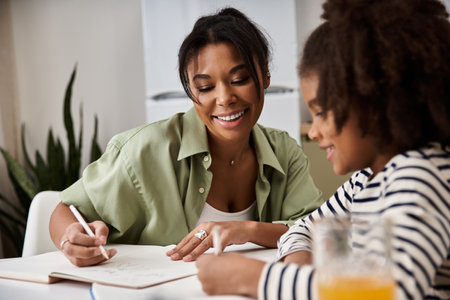 Mother and daughter share joyful moments while drawing together at the kitchen table.の写真素材
