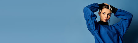 A young woman models trendy outfits against a blue studio backdrop.