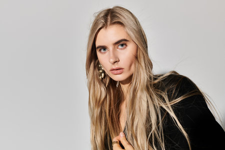 A beautiful blonde woman with long hair poses confidently in black attire, exuding style and grace.の写真素材