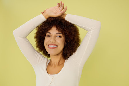 A joyful young woman with curly hair stands confidently in her underwear, radiating happiness...