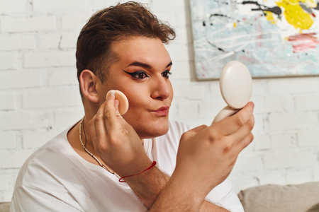 A person with unique style enhances their look using makeup and a mirror in a cozy setting.の写真素材