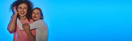 Two happy women showcase their love and diversity against a vibrant pink background, radiating joy.の写真素材