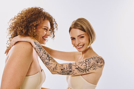 Two joyful women share a tender moment, embracing each other and showcasing their natural beauty and love.の写真素材