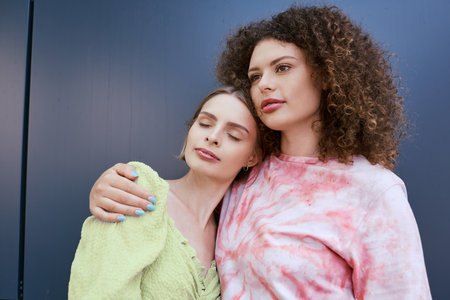 Two young women share a loving embrace, radiating joy and connection in a colorful setting.の写真素材