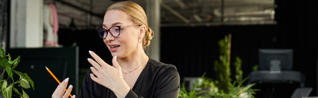 A young woman in an office setting passionately discusses ideas while holding a pencil.の写真素材