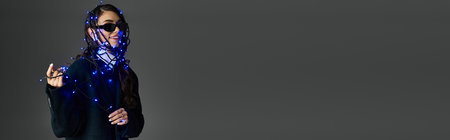 Pretty woman elegantly draped in blue lights, showcasing playful charm and artistic flair.の写真素材