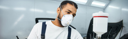 Young mechanic works diligently with safety gear in a bright workshop.