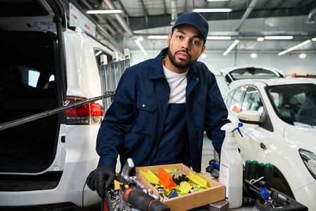 Dedicated mechanic focuses on maintenance tasks while surrounded by various tools and vehicles.の写真素材