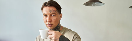 In a relaxed setting, a handsome young man savoring a warm cup of coffee at home.の写真素材