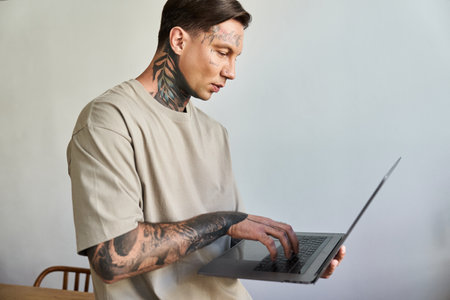 A young handsome man focuses intently on his laptop, surrounded by a cozy home atmosphere.の写真素材