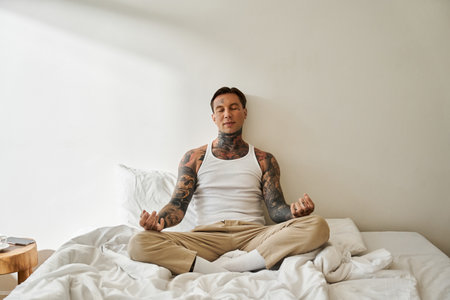 A handsome young man sits cross legged on his bed, deeply engaged in meditation.の写真素材