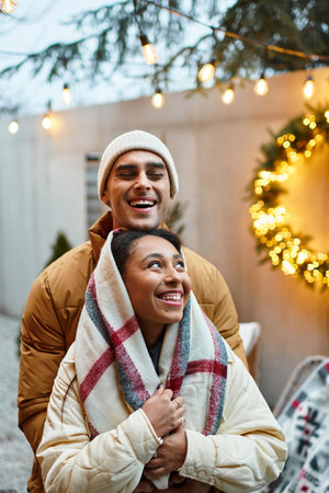 A couple enjoys each others company outdoors, surrounded by Christmas lights and decorations.の写真素材