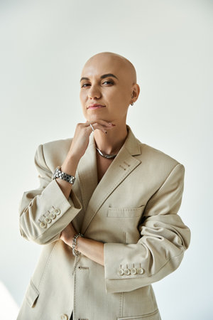 A confident young woman with alopecia shines in stylish beige attire, showcasing her beauty.の写真素材