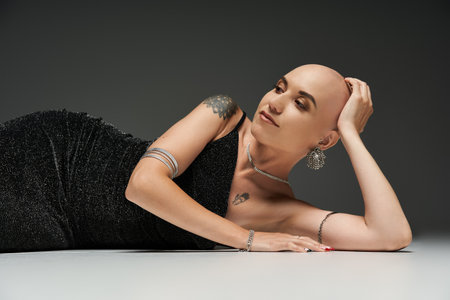 A confident young woman with alopecia lounges gracefully, showcasing her unique beauty.