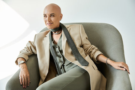 A young woman with alopecia radiates confidence, dressed elegantly and seated comfortably.の写真素材