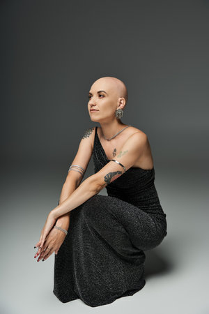 A confident young woman with alopecia sits gracefully, showcasing her elegance and beauty.の写真素材