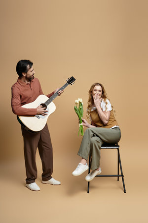 A joyful moment unfolds as a man plays guitar for a woman holding flowers in a cozy atmosphere.の写真素材