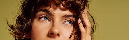 The young woman gazes thoughtfully with a mix of emotions on her face, showcasing her curls.の写真素材