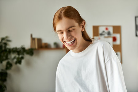 A young man with long hair smiles widely, embodying happiness while enjoying friendly company.の写真素材