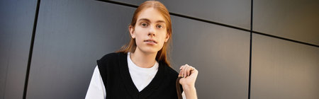 A young man stands against a sleek, contemporary backdrop, showcasing his unique style.の写真素材