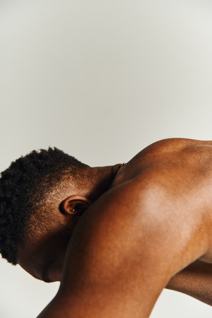 A young handsome african american man strikes a confident pose without a shirt, showcasing his body....