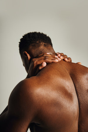 A young, handsome African American man stands confidently, showcasing his toned physique.の写真素材