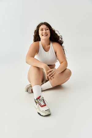 Young plus size woman showcases her confidence in fashionable underwear while sitting gracefully.の写真素材