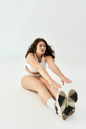 A young plus size woman stretches gracefully in trendy underwear, exuding confidence and beauty.の写真素材